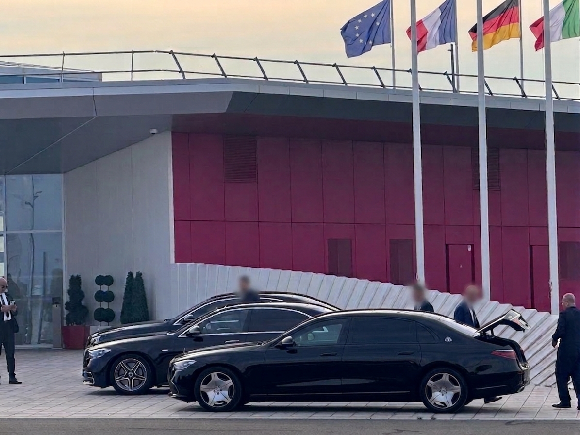Berlines Mercedes-Maybach alignées devant un bâtiment officiel pavoisé aux couleurs de l'Union européenne, de la France, de l'Allemagne et de l'Italie, pour l'accueil d'une délégation internationale
