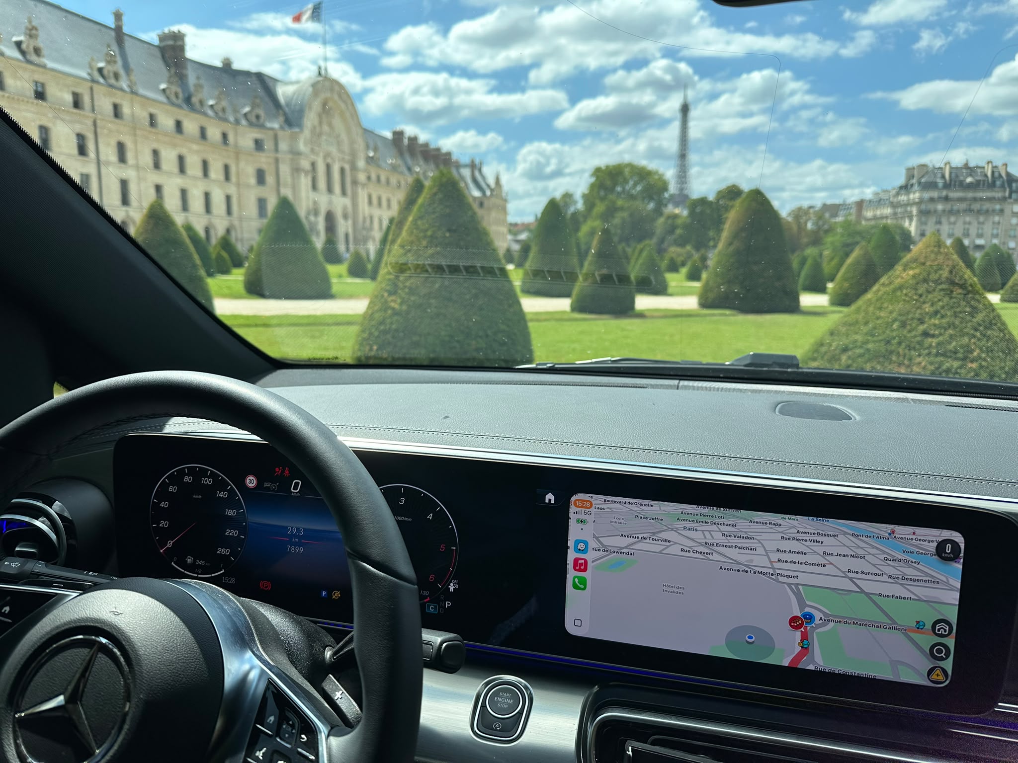 Vue depuis l'habitacle d'une berline Francelimo, navigation GPS à l'écran, Tour Eiffel et Esplanade des Invalides en arrière-plan